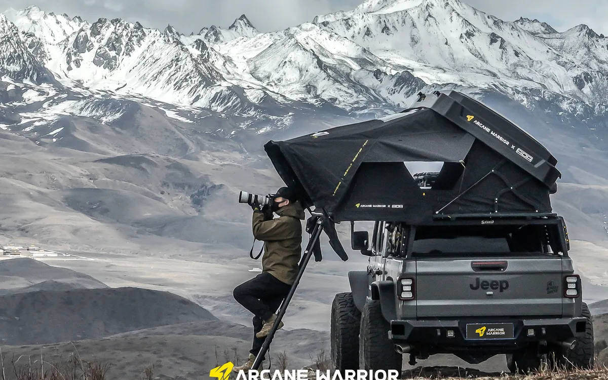 Open LANDING roof tent on a Jeep in front of snowy mountains