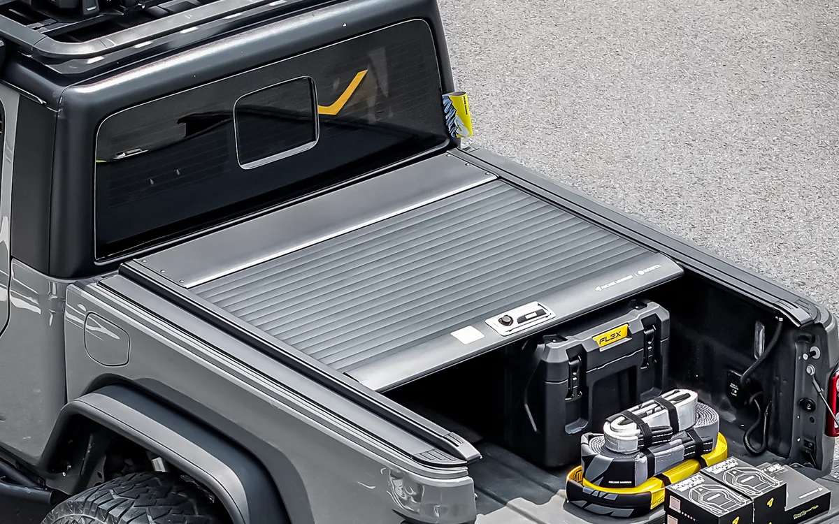 Partly open roll-up load bed cover on a pickup with storage cases in the bed