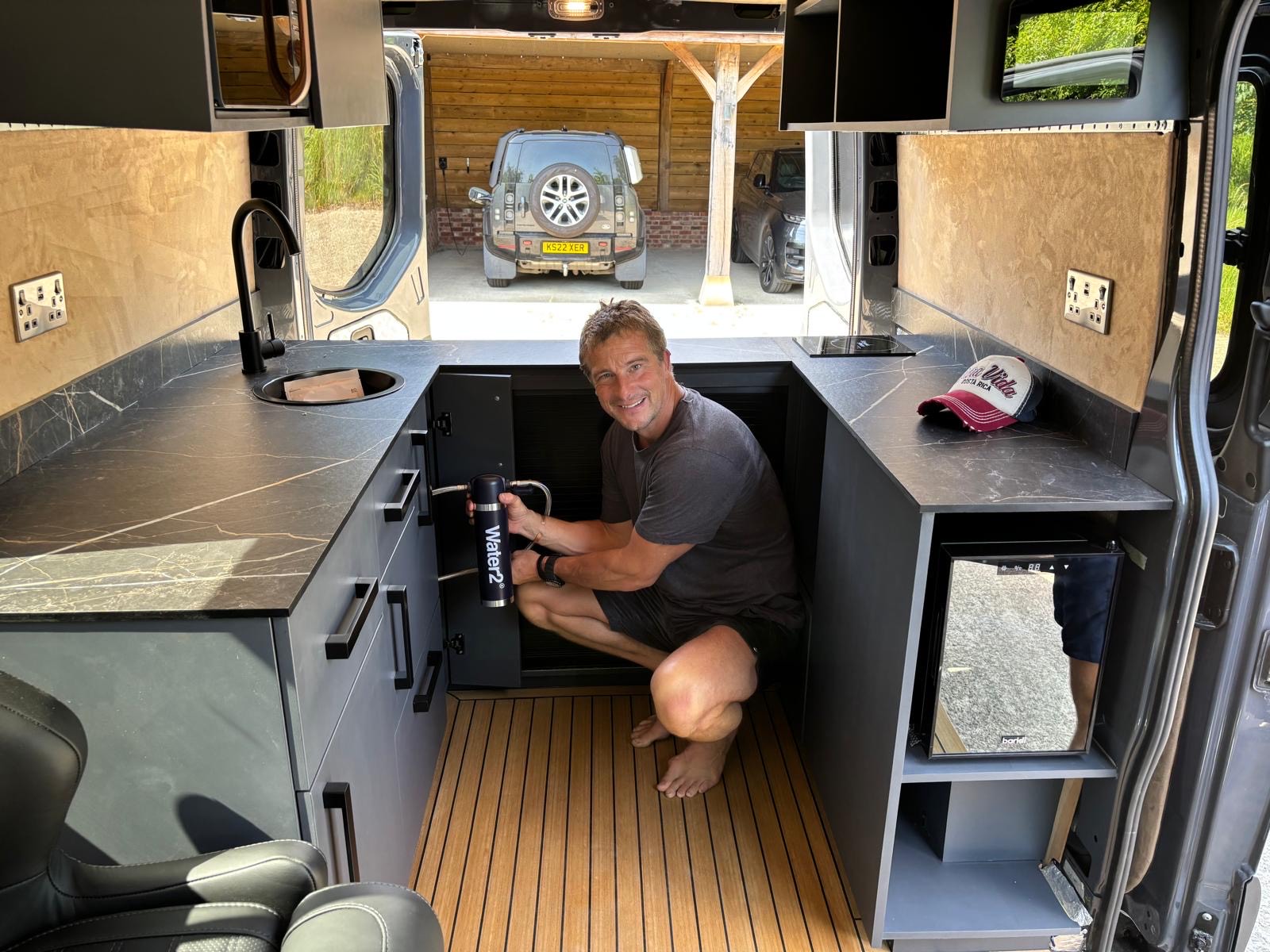 Bear Grylls with Apollo van examining the Water2 filter system