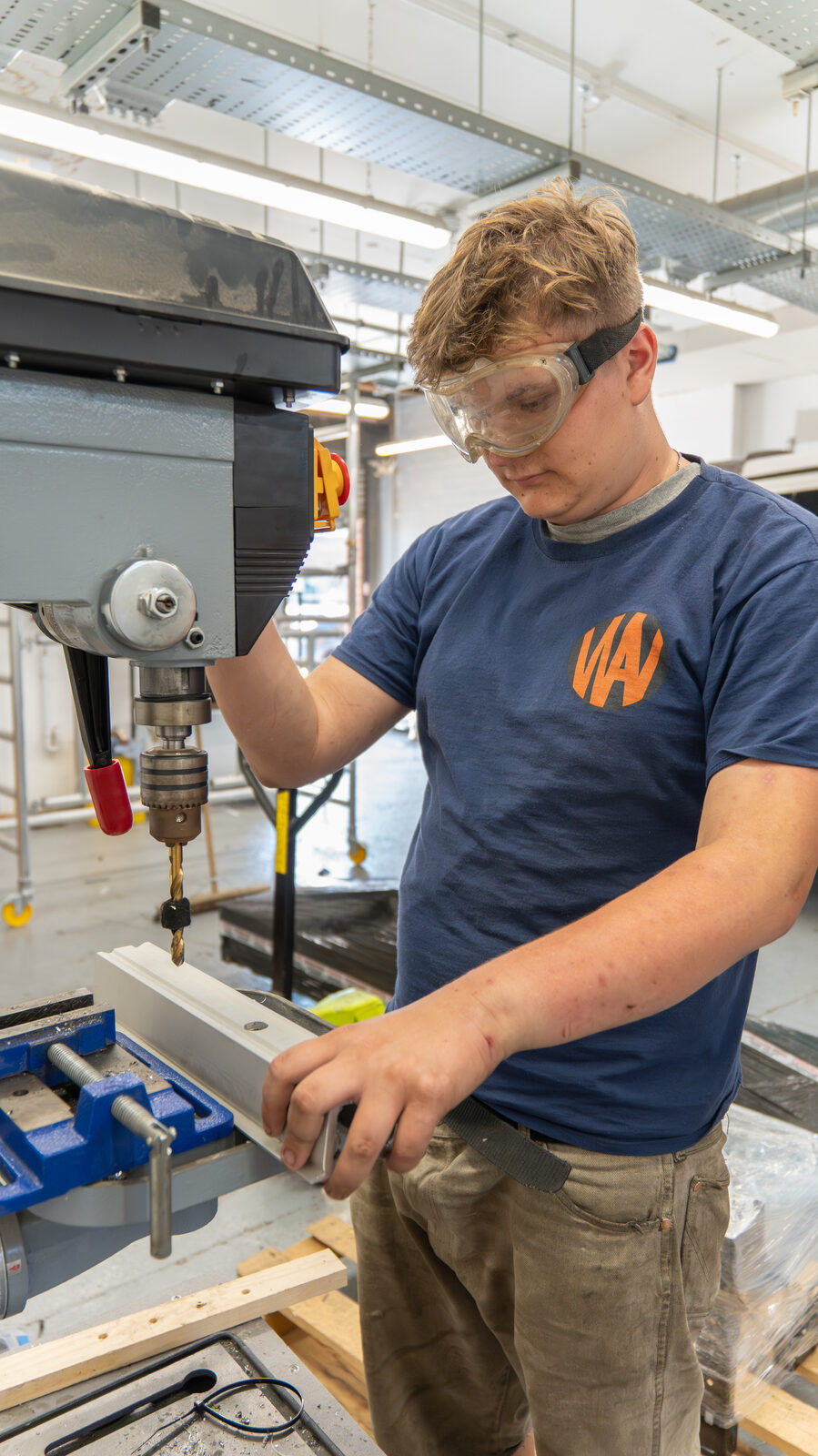 Alfie working at a drill press in the workshop